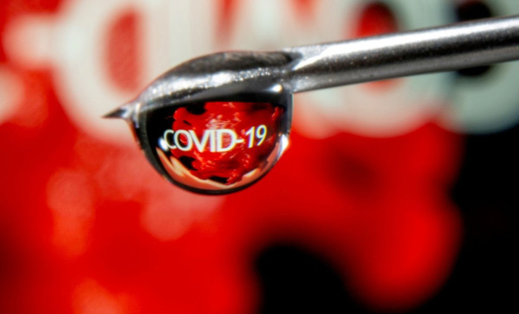 The word "COVID-19" is reflected in a drop on a syringe needle in this illustration taken November 9, 2020. 