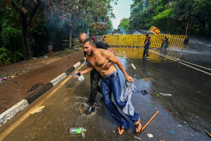 A demonstrator helps another as police use tear gas and water cannon to disperse students demanding the resignation of Sri Lanka's President Gotabaya Rajapaksa over the country's crippling economic crisis, near parliament in Colombo on May 6, 2022