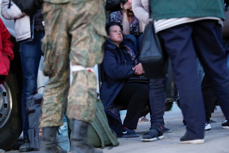 A service member of pro-Russian troops stands in front of people, who were evacuated from Mariupol in the course of Ukraine-Russia conflict, outside a bus near a temporary accommodation centre in the village of Bezimenne in the Donetsk region, Ukraine May