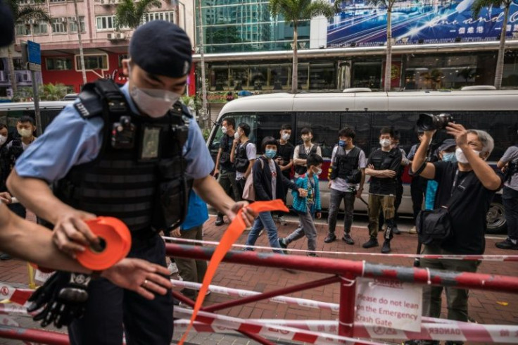 A Hong Kong police officer sets up a cordon before a three-person protest against the selection process of the city's chief executive