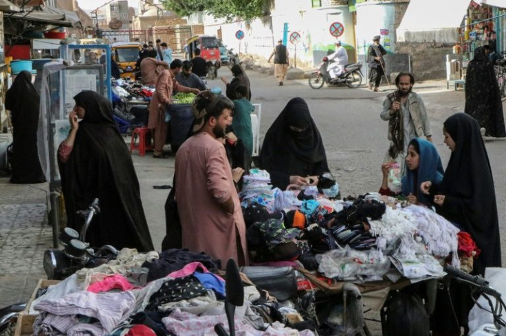 Women buy garments from a street stall in Herat