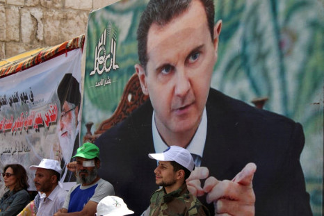 Syrians and Palestinians living in Syria stand next to a poster depicting Syria's President Bashar al-Assad as they mark the annual al-Quds Day (Jerusalem Day), in Damascus, Syria April 29, 2022. 