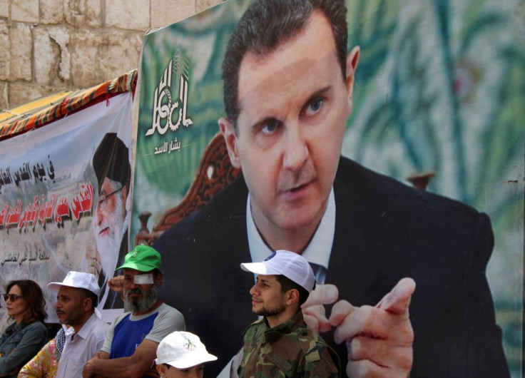 Syrians and Palestinians living in Syria stand next to a poster depicting Syria's President Bashar al-Assad as they mark the annual al-Quds Day (Jerusalem Day), in Damascus, Syria April 29, 2022. 