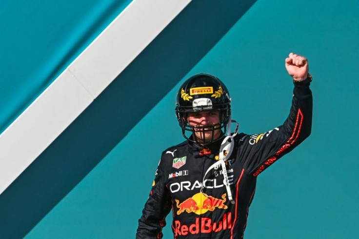 Max Verstappen celebrates on the podium in a gridiron helmet after the winning the Miami Grand Prix, held in the shadow of the Miami Dolphins' stadium