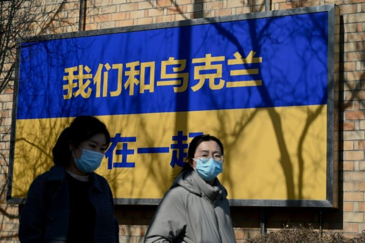 People walk past a sign in the design of Ukraine's flag with the message "We Support Ukraine" outside the Canadian embassy in Beijing in March 2022