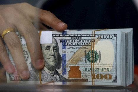 An employee of a money changer holds a stack of U.S. dollar notes before giving it to a customer in Jakarta, October 8, 2015. 
