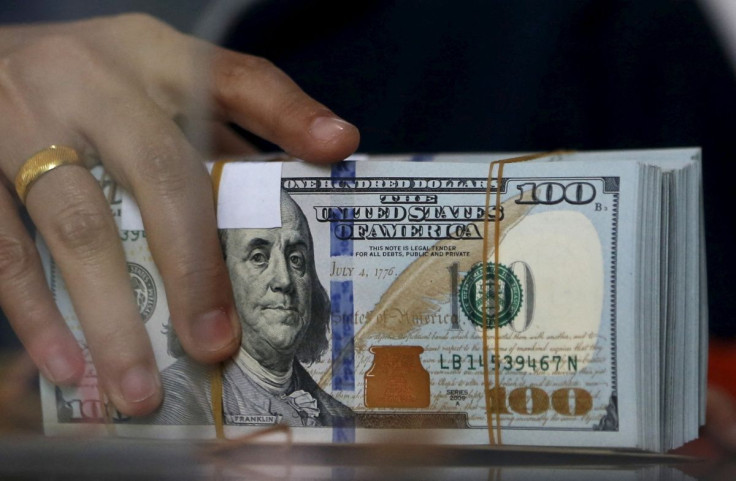 An employee of a money changer holds a stack of U.S. dollar notes before giving it to a customer in Jakarta, October 8, 2015. 