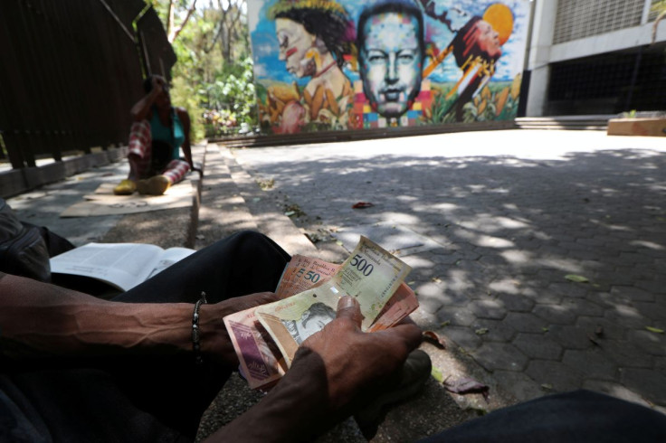 A local counts Venezuelan Bolivar notes in front of a mural depicting the late Venezuelan President Hugo Chavez in Caracas, Venezuela March 14, 2019. 