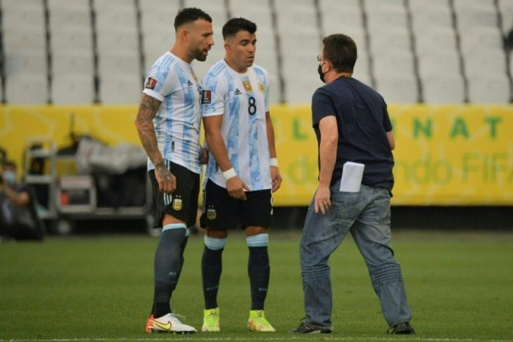 An employee of the Brazilian National Health Surveillance Agency (Anvisa) argues with Argentina's Nicolas Otamendi (L) and Marcos Acuna as the the World Cup Qatar qualifier in Sao Paul was halted