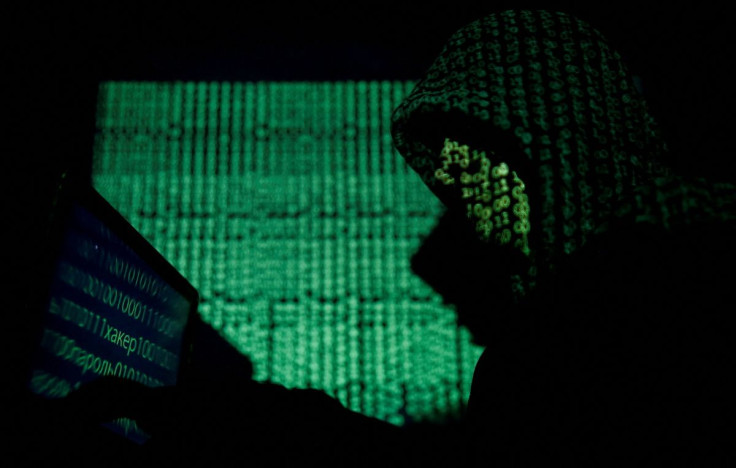 A hooded man holds a laptop computer as cyber code is projected on him in this illustration picture taken on May 13, 2017. 