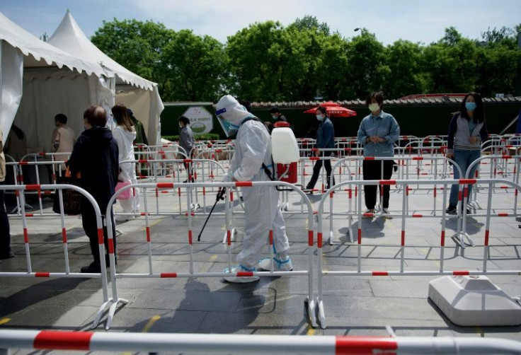 A worker disinfects the queue area of a swab test collection site in Beijing