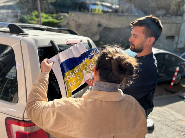 Maria Belkina and her partner Kirill Zhivoi, co-founders of Volunteers Tbilisi, a group which helps refugees from Ukraine, stick a sign with the Ukrainian flag onto a vehicle in Tbilisi, Georgia April 15, 2022. Maria Belkina/Handout via REUTERS