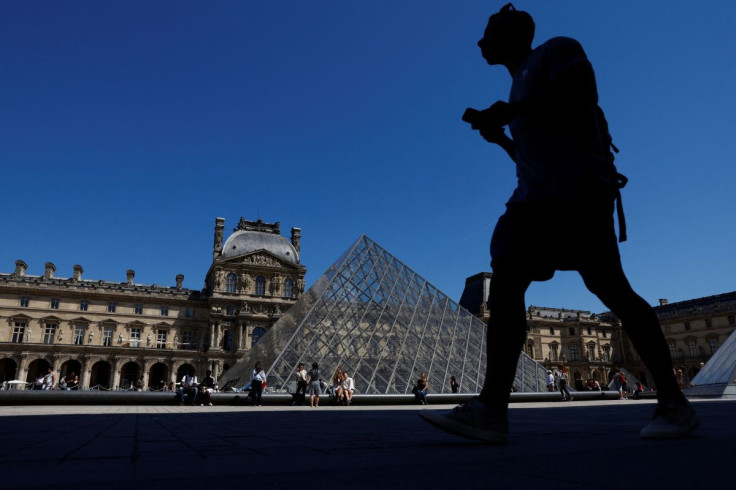 A man walks near the glass Pyramid of the Louvre museum on a sunny day in Paris, France, May 11, 2022.