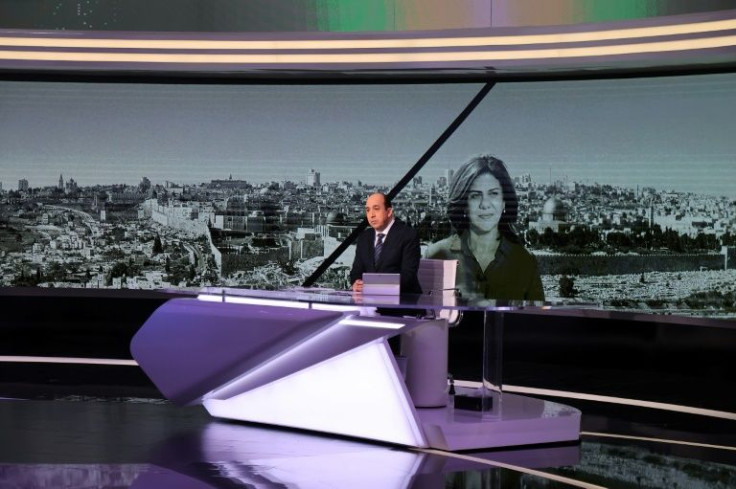 Al Jazeera's Moroccan journalist Abdel Samad Nasser broadcasts a report before an image of his network colleague Shireen Abu Akleh at the Qatari news broadcaster's main headquarters in the capital Doha