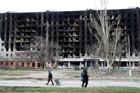 Local residents walk past a burned building during Ukraine-Russia conflict in the southern port city of Mariupol, Ukraine April 4, 2022. 