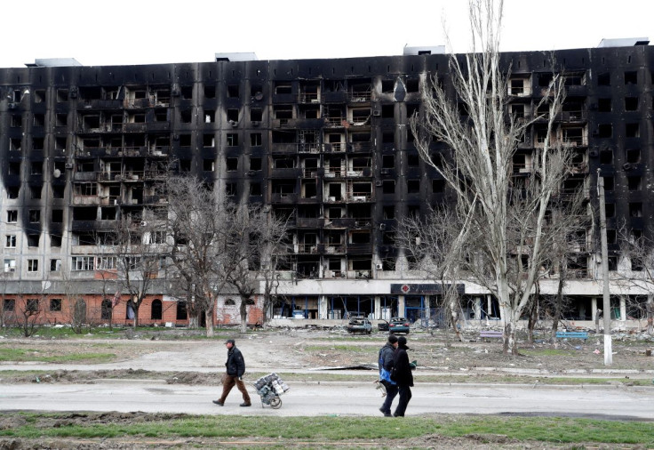 Local residents walk past a burned building during Ukraine-Russia conflict in the southern port city of Mariupol, Ukraine April 4, 2022. 