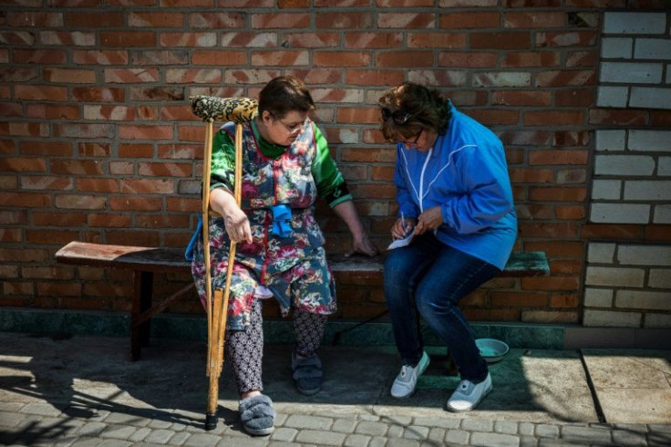 Social worker Zhanna Protsenko writes down a list of things that she will pick up for Nyna Provontsova who has problems with her legs cannot cope on her own