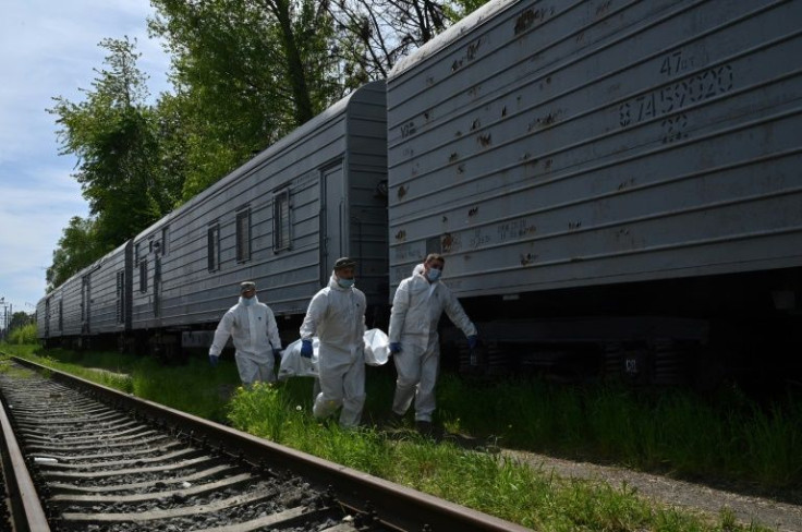 Bodies are exhumed and stored in a string of refrigerated rail cars stacked with the Russian dead
