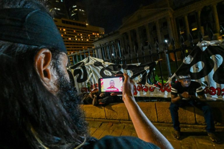 A protester in Colombo watches an address to the nation by Sri Lanka's President Gotabaya Rajapaksa near the president's office