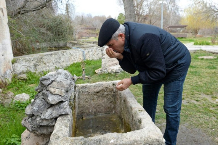 Returning refugee Ali Hasanov drinks water from a fountain in Aghdam on his first trip home, 29 years after he was forced to free Karabakh
