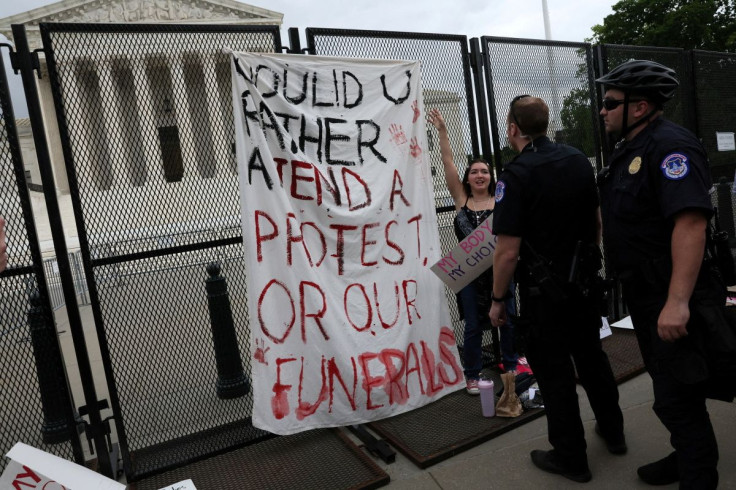 U.S. Capitol Police officers take down the banner brought by Summer Elizabeth Brouwer as she stands next to it while people rally for abortion rights after an anti-climb protective fence was installed outside of the U.S. Supreme Court building in Washingt