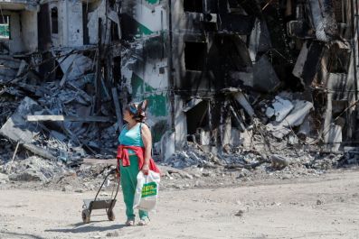 A woman stands near a residential building destroyed during Ukraine-Russia conflict in the southern port city of Mariupol, Ukraine May 12, 2022. 