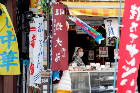 A woman wearing protective mask waits for customers at a market district in Tokyo, Japan May 13, 2020.