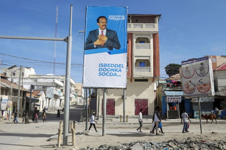 People walk past an election banner of incumbent Somali President Mohamed Abdullahi Mohamed in Mogadishu, Somalia May 12, 2022.