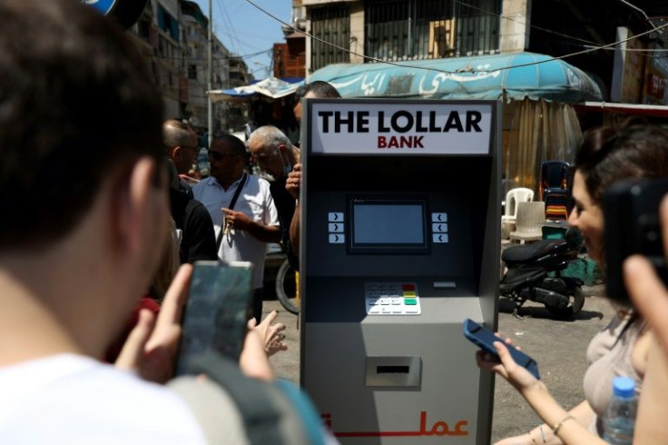 Lebanese surround a mock ATM, distributing fake banknotes called "lollars"