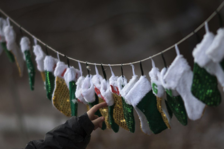 A boy touches stockings, representing those killed in the December 14 shootings at Sandy Hook Elementary School, on Christmas morning in Sandy Hook Village in Newtown, Connecticut December 25, 2012.  