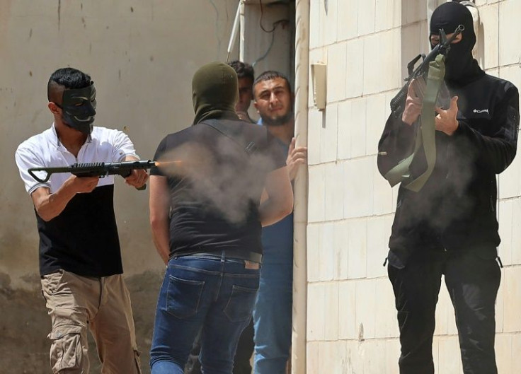 A masked Palestinian man fires an automatic weapon during clashes with Israeli security forces in the West Bank city of Jenin on Friday