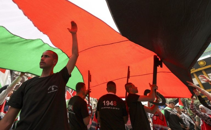 Palestinians march under a huge flag in the occupied West Bank city of Ramallah to mark the "Nakba", or catastrophe of Israel's creation 74 years ago