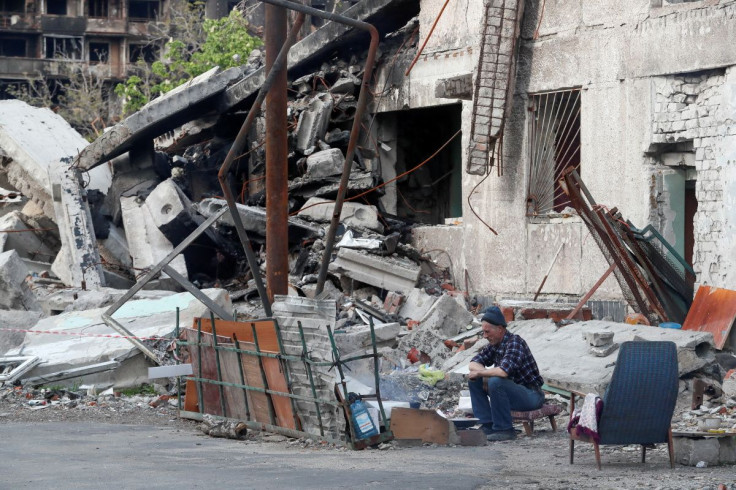 A local resident sits in a courtyard outside a building heavily damaged during Ukraine-Russia conflict in the southern port city of Mariupol, Ukraine May 15, 2022.