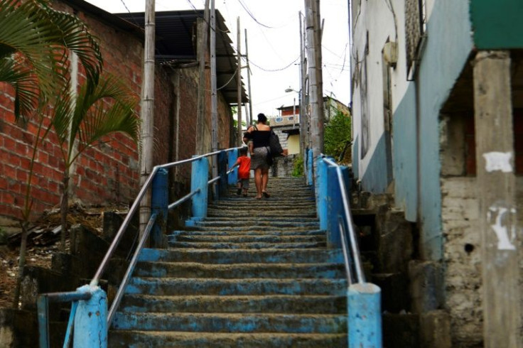 A woman carrying a child and a little boy climb stairsin Cerro Las Cabras, Duran municipality, Ecuador, on April 26, 2022, a area which has a reputation for violence