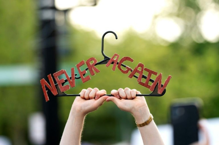 A demonstrator holds up a clothes hanger marked 'Never Again' during an abortion rights rally May 3, 2022 outside the US Supreme Court