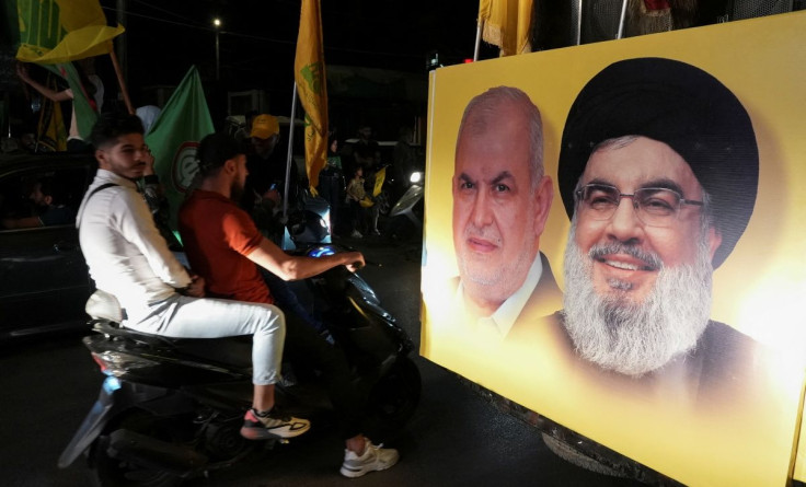 Supporters carry Hezbollah and Amal Movement flags as they ride in a convoy past a poster depicting Hezbollah leader Sayyed Hassan Nasrallah and Head of Hezbollah's parliamentary bloc Mohamed Raad, as votes are being counted in Lebanon's parliamentary ele