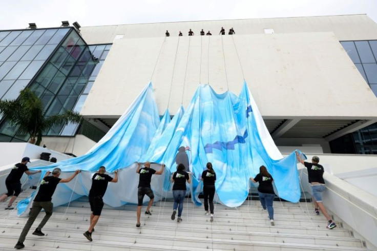 Workers set up the official poster for the 75th Cannes Film Festival on the facade of the Palais des Festivals