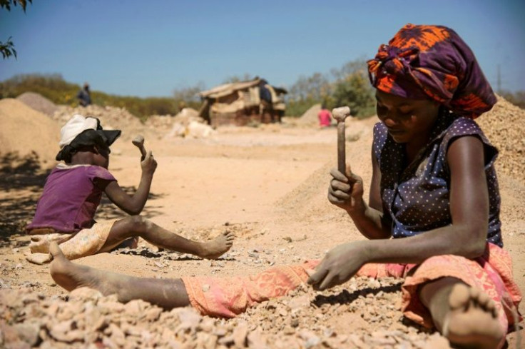 A child and a woman breaking rocks extracted from a cobalt mine in Lubumbashi, DR Congo, in 2016