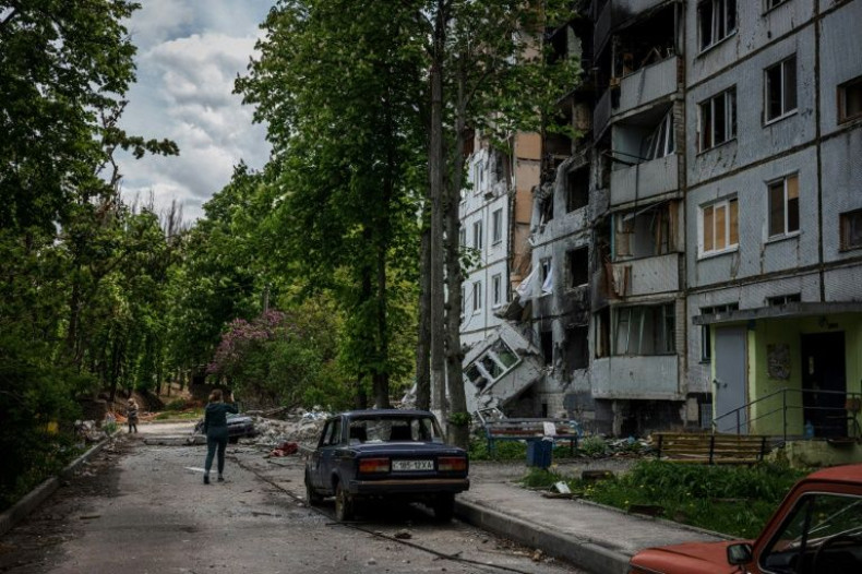 People walk past a damaged residential building in northern Kharkiv, where Russian troops have been beaten into retreat by Ukrainian forces