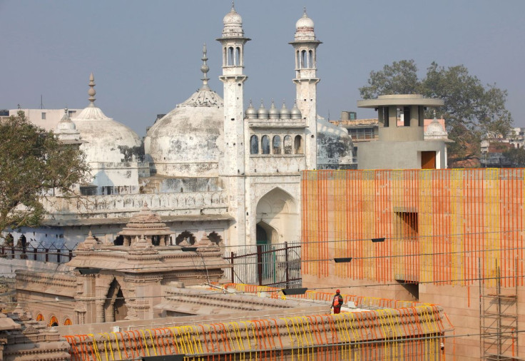 A worker stands on a temple rooftop adjacent to the Gyanvapi Mosque in the northern city of Varanasi, India, December 12, 2021. 