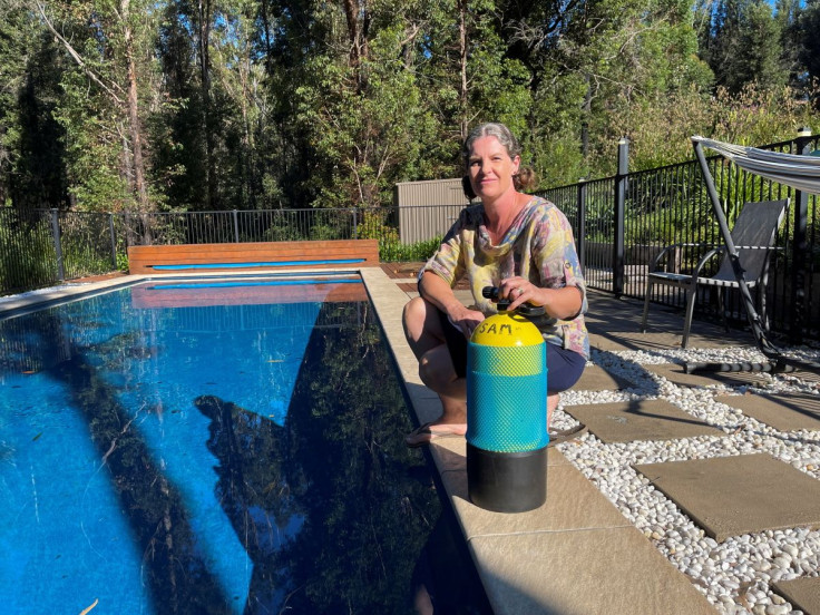 Local resident Samantha Kneeshaw poses with the scuba tank she submerged herself with for survival as bushfires burnt around her home during the "Black Summer," in Conjola, Australia, April 20, 2022. Picture taken April 20, 2022. 
