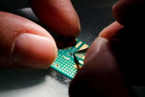 A researcher plants a semiconductor on an interface board during a research work to design and develop a semiconductor product at Tsinghua Unigroup research centre in Beijing, China, February 29, 2016.  