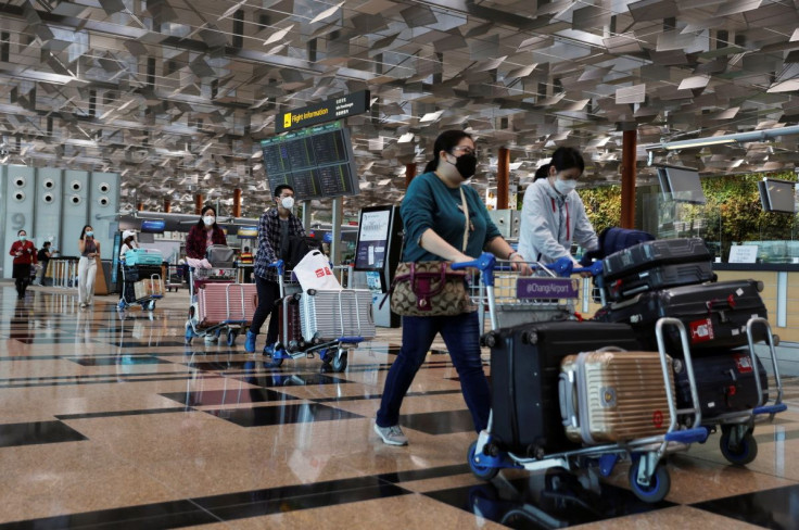 Travellers walk with their luggage at the Changi Airport in Singapore March 30, 2022.