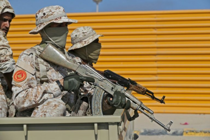 Fighters loyal to Libya's Tripoli-based Prime Minister Abdulhamid Dbeibah sit with their arms in the back of a pickup truck in the capital Tripoli on May 17, 2022