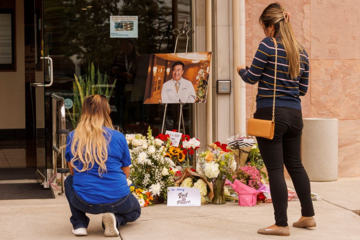 Healthcare workers pause after placing flowers at the entrance to the building where Dr. John Cheng, a 52-year-old victim who was killed in Sunday's shooting at Geneva Presbyterian Church, worked in Aliso Viejo, California, U.S. May 17, 2022.