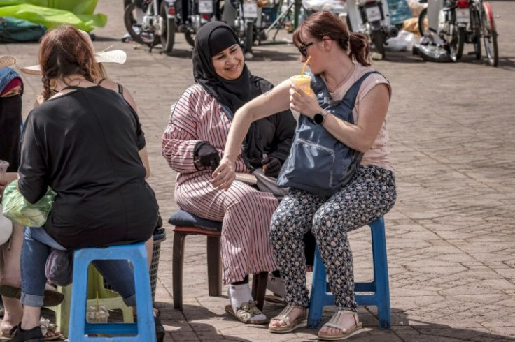 A henna tattoo artist draws on a tourist's arm in Jemaa el-Fnaa square in Marrakesh