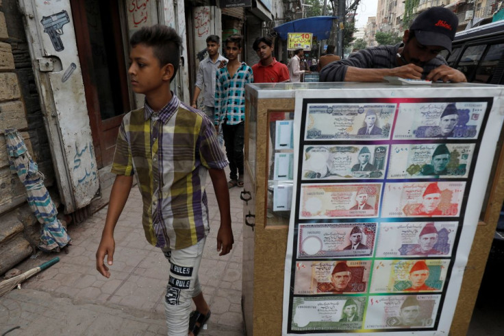 A boy walks past a sidewalk money exchange stall decorated with pictures of banknotes in Karachi, Pakistan September 30, 2021. 