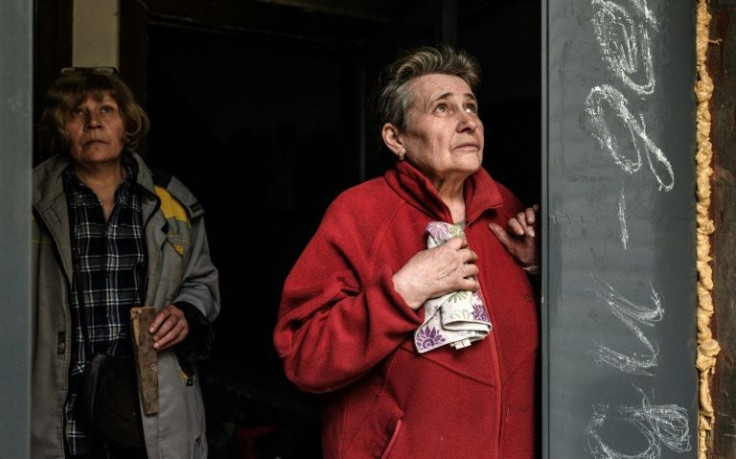 Anna Poladyuk (R) takes cover by the entrance to an apartment basement after hearing incoming mortar fire, followed by an explosion, in Severodonetsk, eastern Ukraine