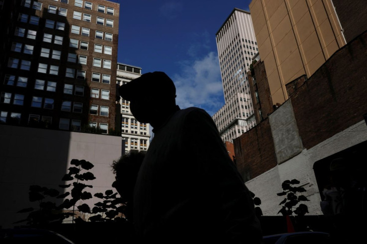 A man is seen silhouetted wearing a protective face mask, amid the coronavirus disease (COVID-19) pandemic, walking near the financial district of New York City, U.S., October 18, 2021. 