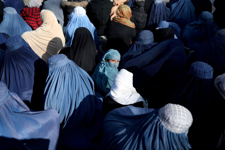 A girl sits in front of a bakery in the crowd with Afghan women waiting to receive bread in Kabul, Afghanistan, January 31, 2022.